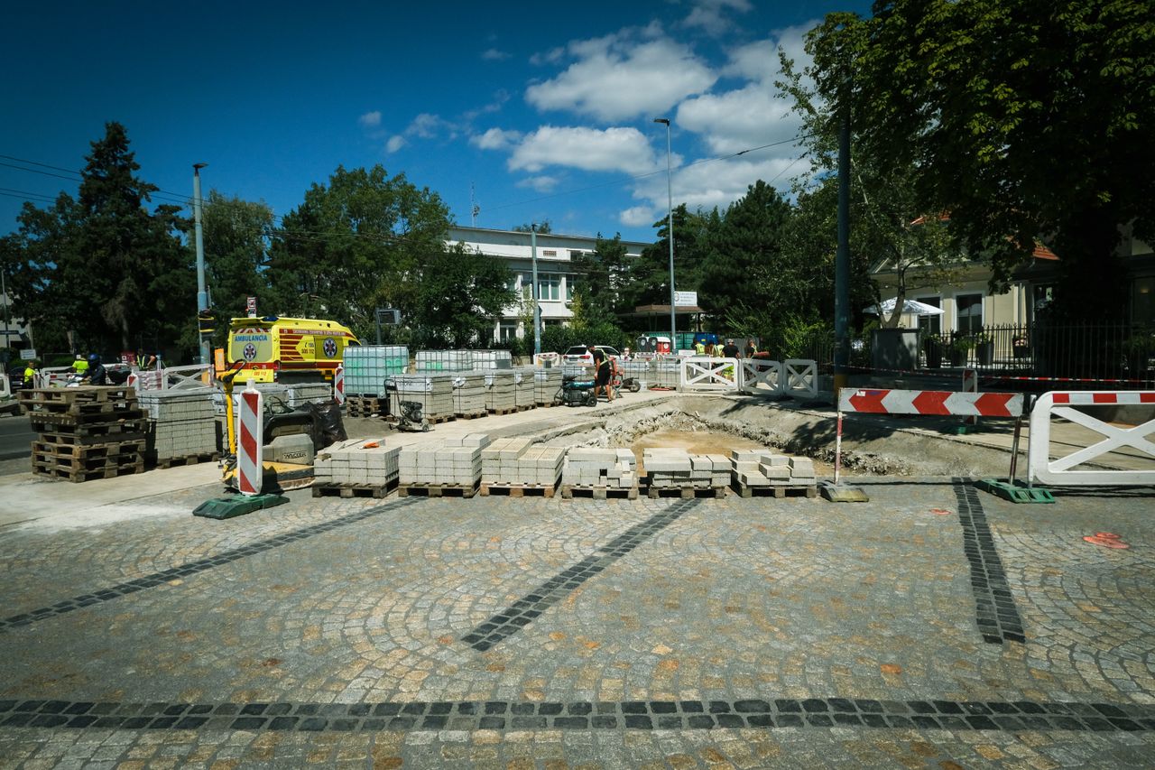 Street construction site in Bratislava with paving stones and machinery under clear blue sky.